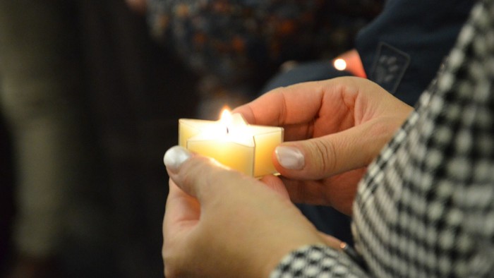 Eine Trauernde hält ein sternförmiges Teelicht in ihren Händen.