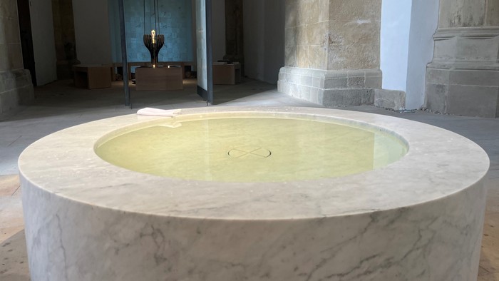 Man sieht das Taufbecken in der Christuskirche, im Hintergrund der Raum der Stille.