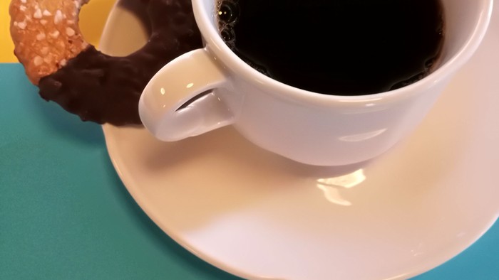 Eine Tasse Kaffee mit zwei Donuts auf einem Unterteller