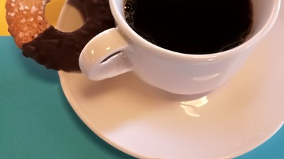 Eine Tasse Kaffee mit zwei Donuts auf einem Unterteller