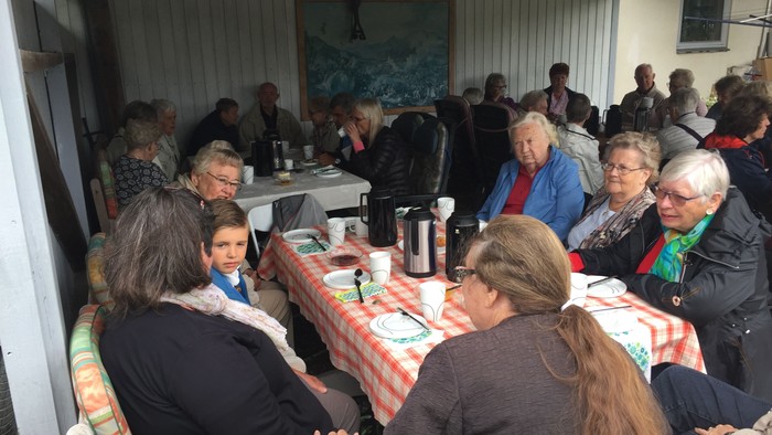 En gruppe af mennesker sidder sammen om bord med mad og drikkevarer.