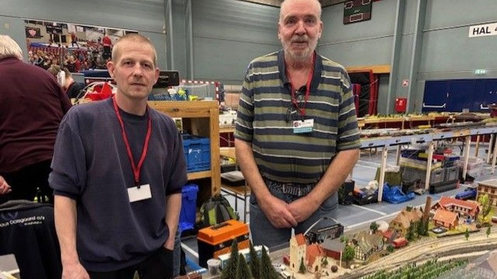 Et billede af to mænd der står bagved en hobby togbane
