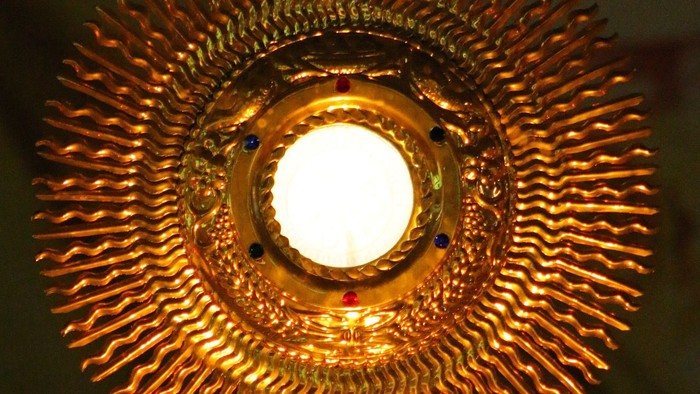 Goldener Leuchter mit Kreuz und hellen Licht.