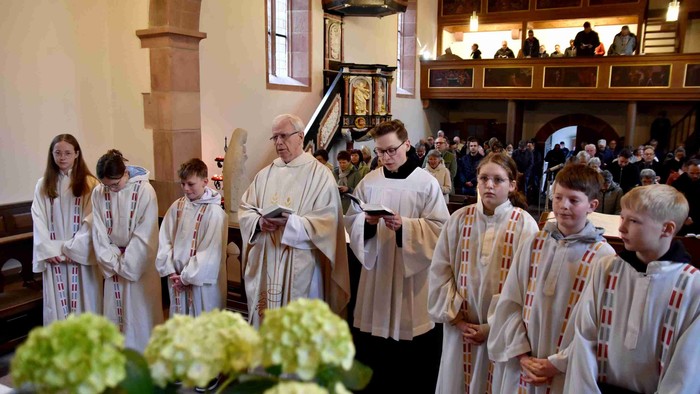 Kinderchor in Kirche singt, Priester leitet