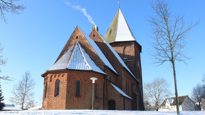 Kirchengebäude aus Ziegeln mit spitzen Dächern im Schnee