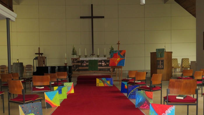 Farbenfrohe Kirche mit rotem Teppich und bunten Stühlen