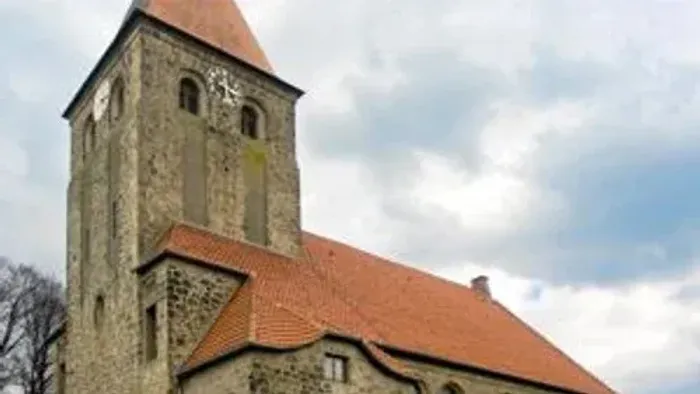 Alte Kirche mit hohem Turm und rotem Dach bei bewölktem Himmel
