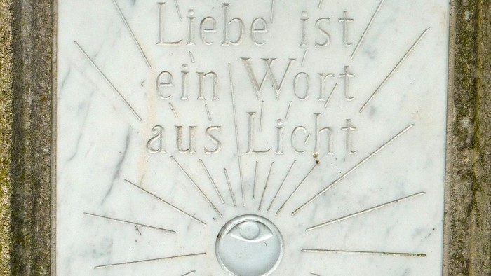 Das Bild zeigt eine Marmorplatte mit der eingravierten Aufschrift "Liebe ist ein Wort aus Licht".