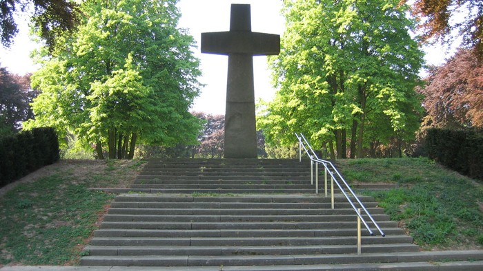 Ein großes Kreuz steht auf einer Treppe in einem Park