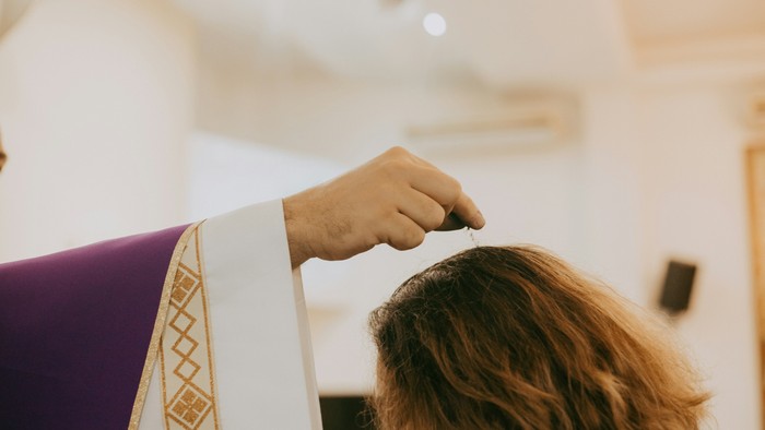 Eine Person schneidet mit einer Schere Haare in einem hellen Raum.