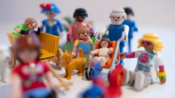 Kleine Plastikfiguren in verschiedenen Outfits und Posen, einige sitzend, andere stehend, eng nebeneinander arrangiert.