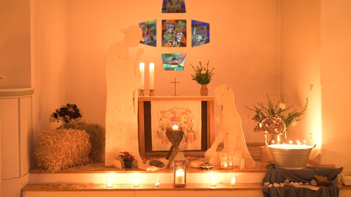 Ein geschmückter Altar mit Kerzen, Blumen und Bildern in einem warmen Raum