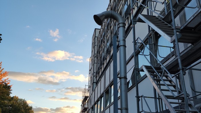 Modernes Gebäude mit Glasfassade und Metallgerüst unter blauem Himmel