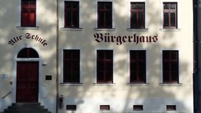 Das Bild zeigt ein weißes Gebäude mit dem Namen "Bürgerhaus" und einem Uhrturm.