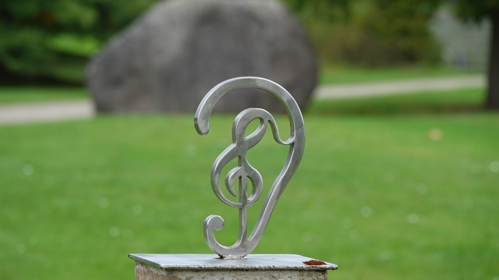 Ein silbernes Musiksymbol auf einem Stein im grünen Garten.
