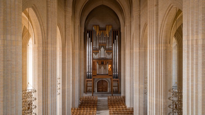 Indre del af en stor kirke med orgel og træbænke.