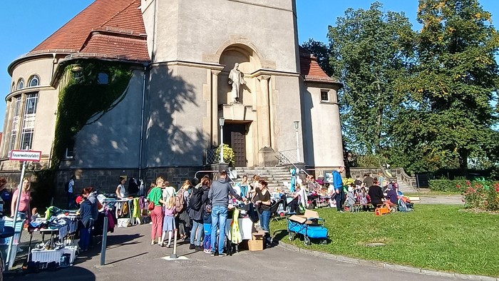 Ein hoher Turm mit Uhr, umgeben von Menschen auf einem Marktplatz