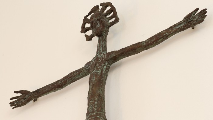 Bronze krucifiks-skulptur med udstrakte arme og en tornekrone på hovedet.