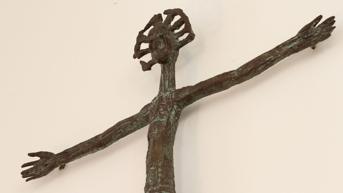 En smedejernskulptur af en figur med udstraktte arme.