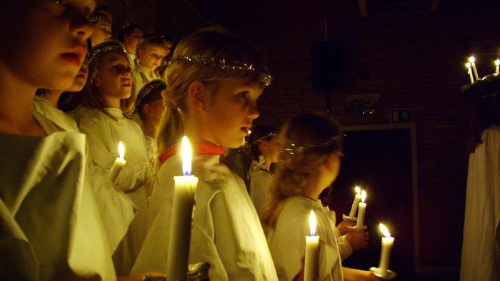 Børn i hvide klerer holder lys.