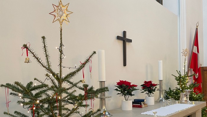 En juletree med pynt og stjerner ved alteret i kirken