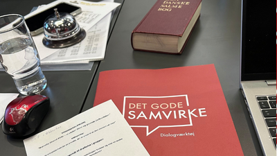 Bog, laptop, glas og papirer på bord med mønstre