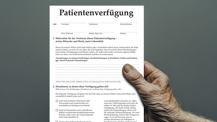 Ein deutsches „Patientenverfügung“-Formular mit einer Hand, die es hält, zur Veranschaulichung von medizinischen Vorausverfügungen.