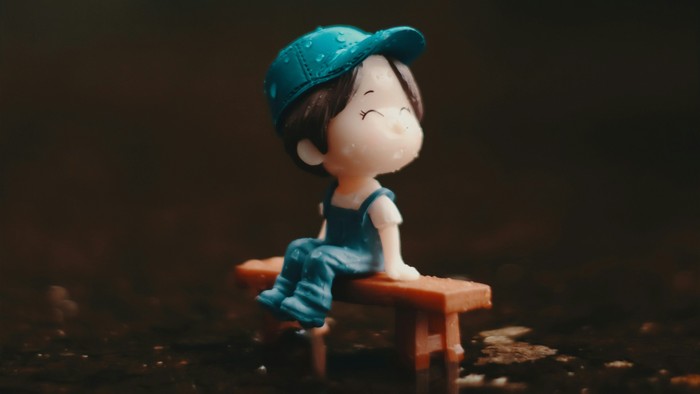 Eine kleine Figur sitzt auf einer Bank im Dunklen.