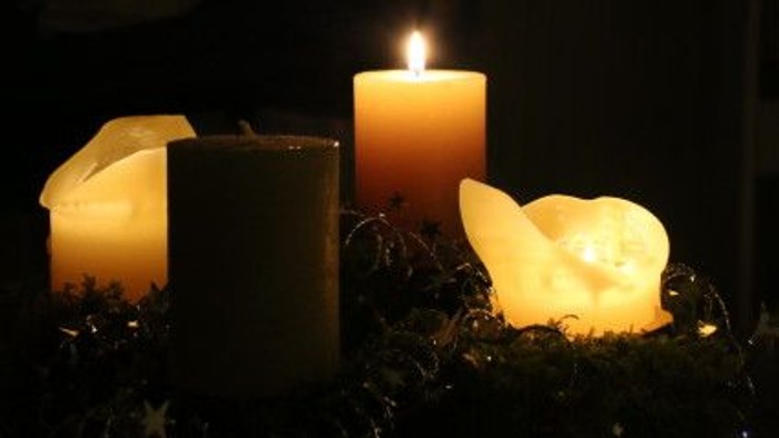 Drei Kerzen und eine Teelicht in einer dunklen Umgebung