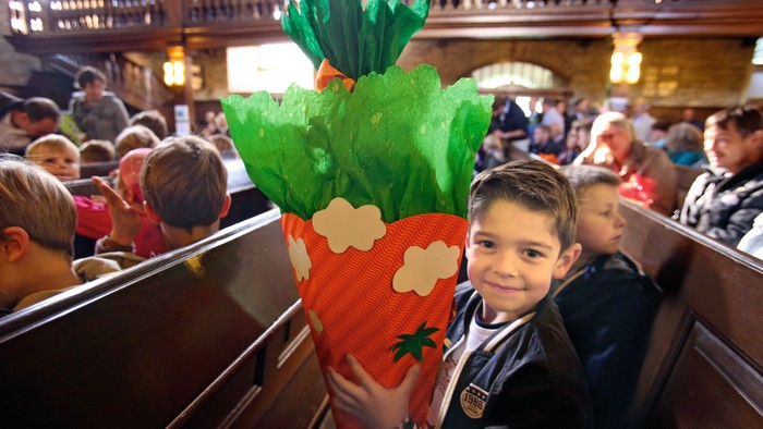 Kind hält große Karotte in Kirche