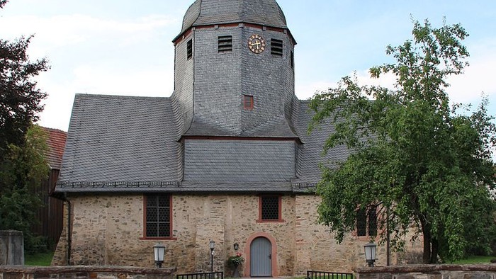 Steinkirche mit hohem Turm und grünem Tor.