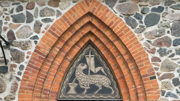 Eingangstür der Dorfkirche Alt-Wittenau, über der Tür ein Opferlamm