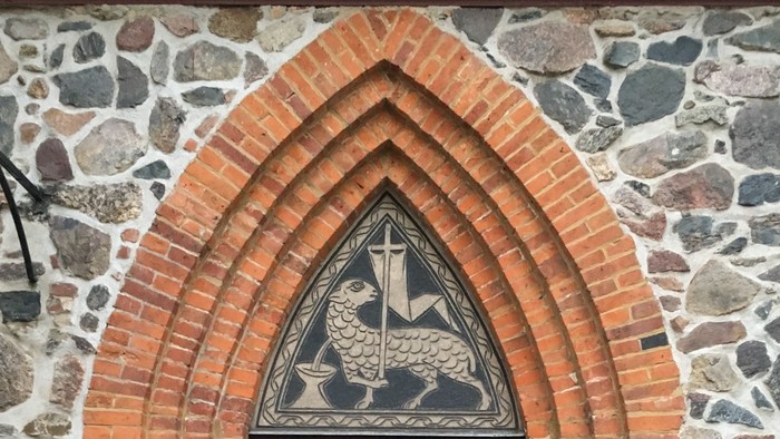 Eingangstür der Dorfkirche Alt-Wittenau, über der Tür ein Opferlamm