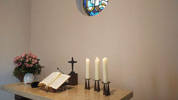 Ein Altar mit Kerzen, Kreuz und Blumen in einem Raum