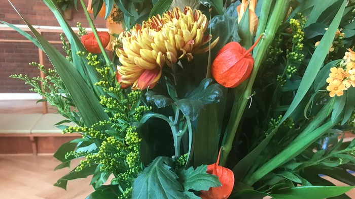 En blomsterstang med gule og røde blomster og grønne blade.