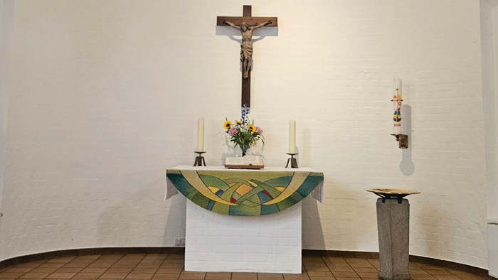 Kleine Kapelle mit farbenfrohen Fenstern und einem Altar mit Kruzifix