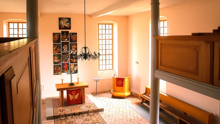 Ein helles, geräumiges Zimmer mit Holzvertäfelung, einem Tisch, einem Kamin und einem großen Fenster.