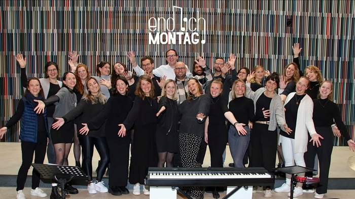 Ein großes Gruppenfoto vor einem Hintergrund mit dem Text 