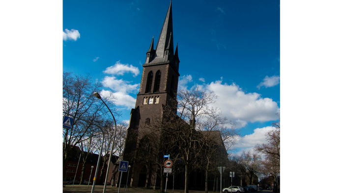 Kirche mit hohem Turmspitz und blauem Himmel.