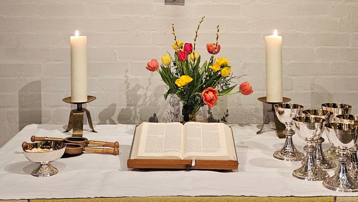 Ein Altar mit Kruzifix, Kerzen und Blumen in einer Kirche