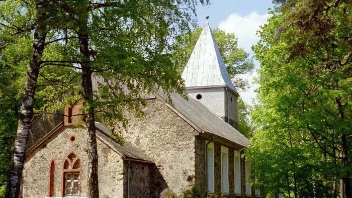 Kirchengemeinde trifft sich vor alter Kirche im Wald.