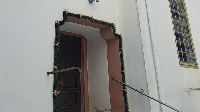 Weißes Kirchengebäude mit schwarzem Dach und Schnee auf den Stufen