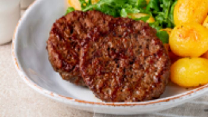 En ret med kød, kartofler og grønne bønner på en hvid tælle.