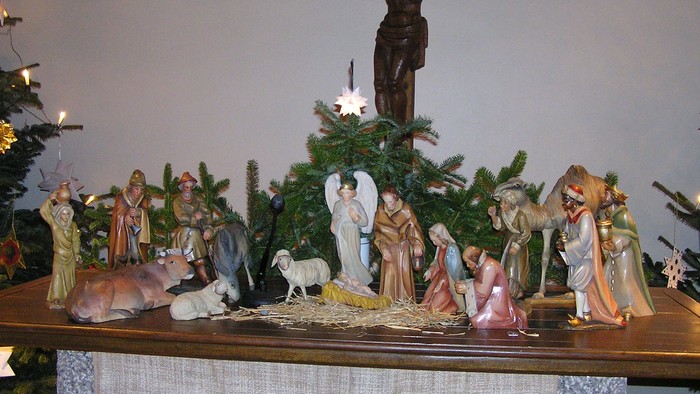 Eine Krippe mit verschiedenen Figuren und einer kleinen Weihnachtsbaumdekoration