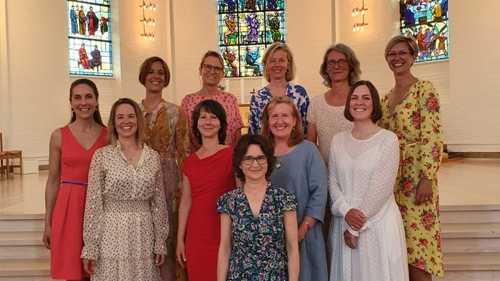 En gruppe kvinder poser i en kirke foran glasmalerier
