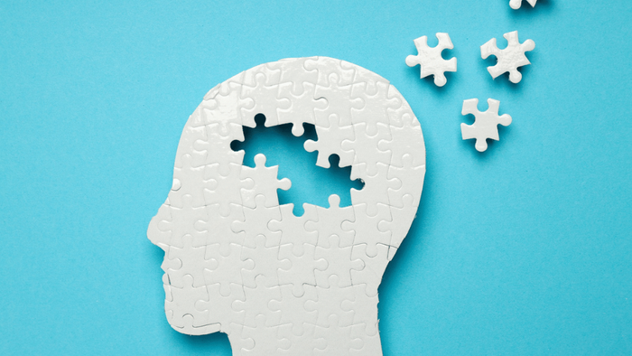 Ein puzzleteilförmiges Gehirn-Silhouett mit zusätzlichen Teilen, die in der Nähe schweben, als Symbol für kognitive Funktionen oder mentale Herausforderungen.