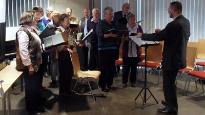 Ein Mann leitet einen Chor, der Noten liest