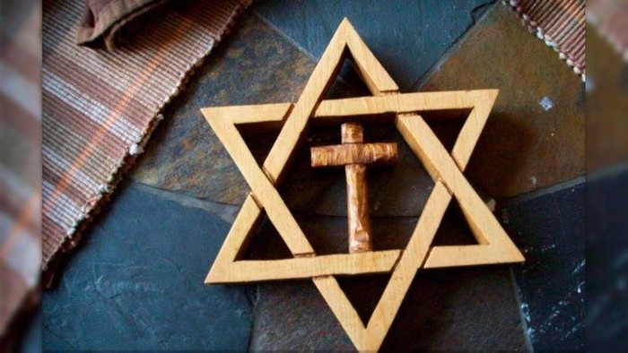 Ein hölzernes Davidstern-Symbol mit Kreuz liegt auf einem Tuch.