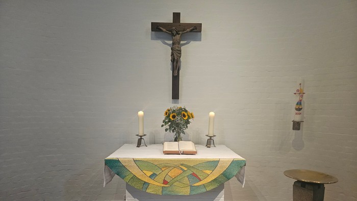 Ein Altar mit Kreuz, Kerzen und Blumen in einem Kirchenraum