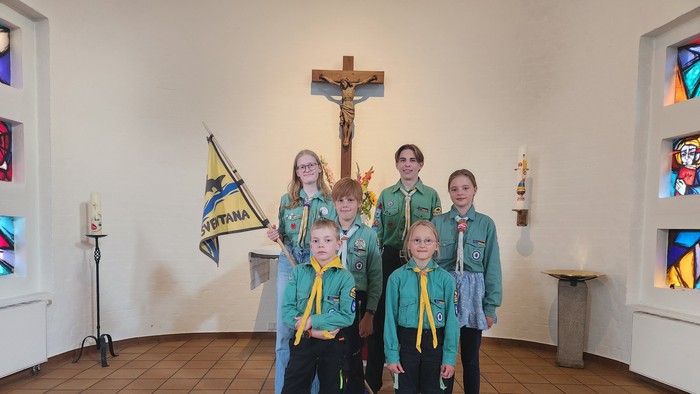 Eine Gruppe von Pfadfindern posiert vor einem Kruzifix in einer Kirche